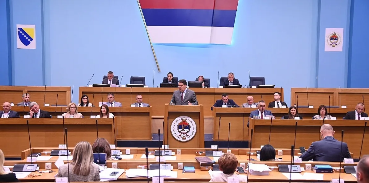 Skupština Republike Srpske sa zastavom iznad govornice i zastupnicima koji sjede u klupama.