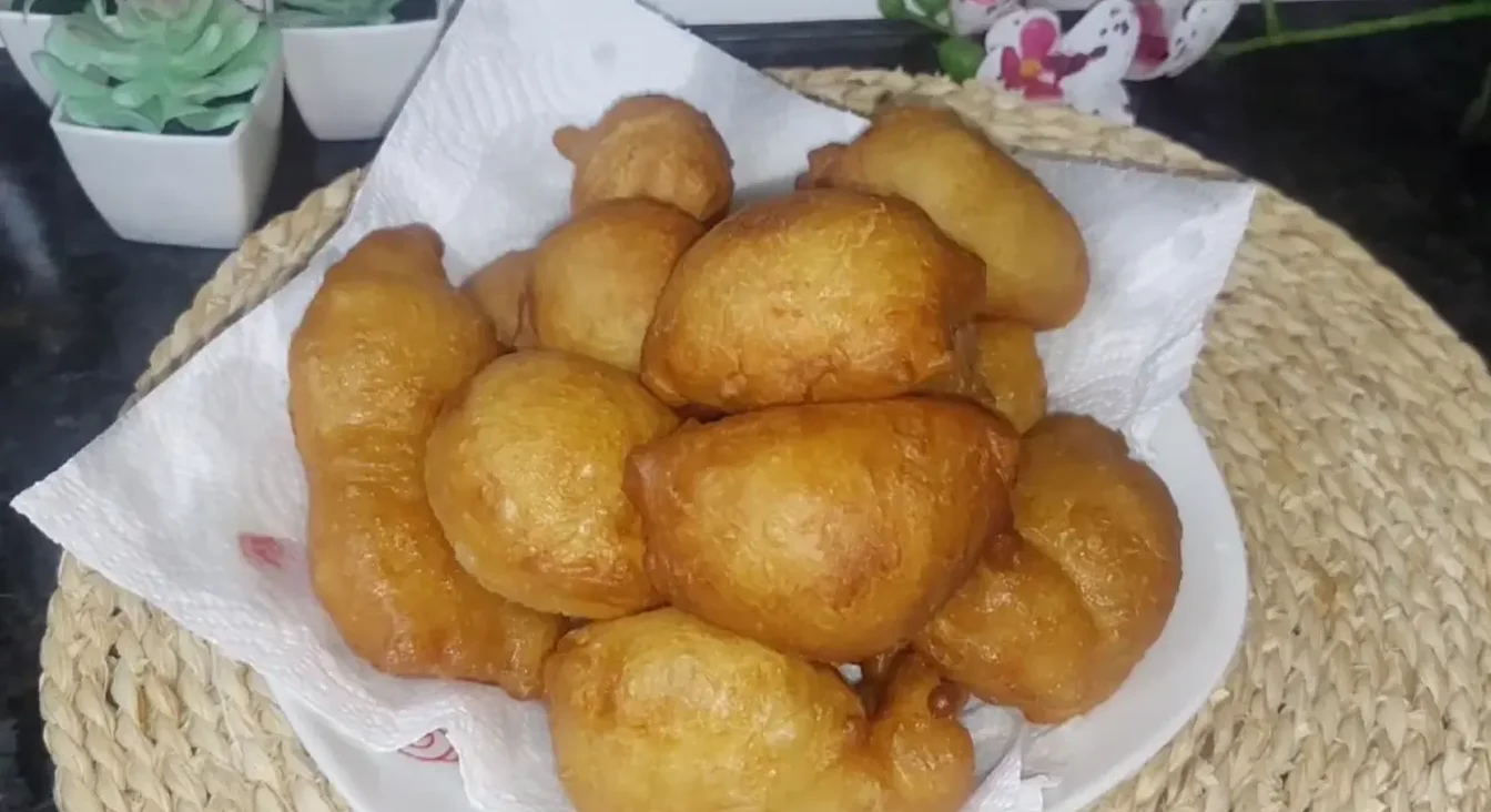 Zlatno-smeđe pržene krofne složene na bijelom tanjiru obloženom papirnim ubrusom.
