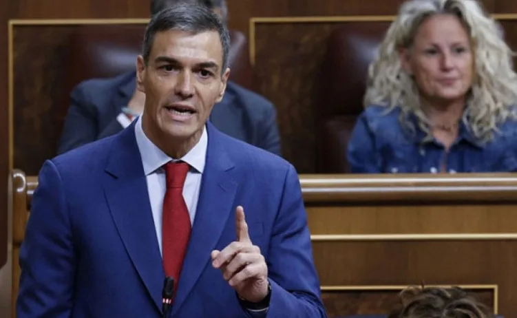Pedro Sánchez, španski premijer, govori u parlamentu noseći plavo odijelo i crvenu kravatu.