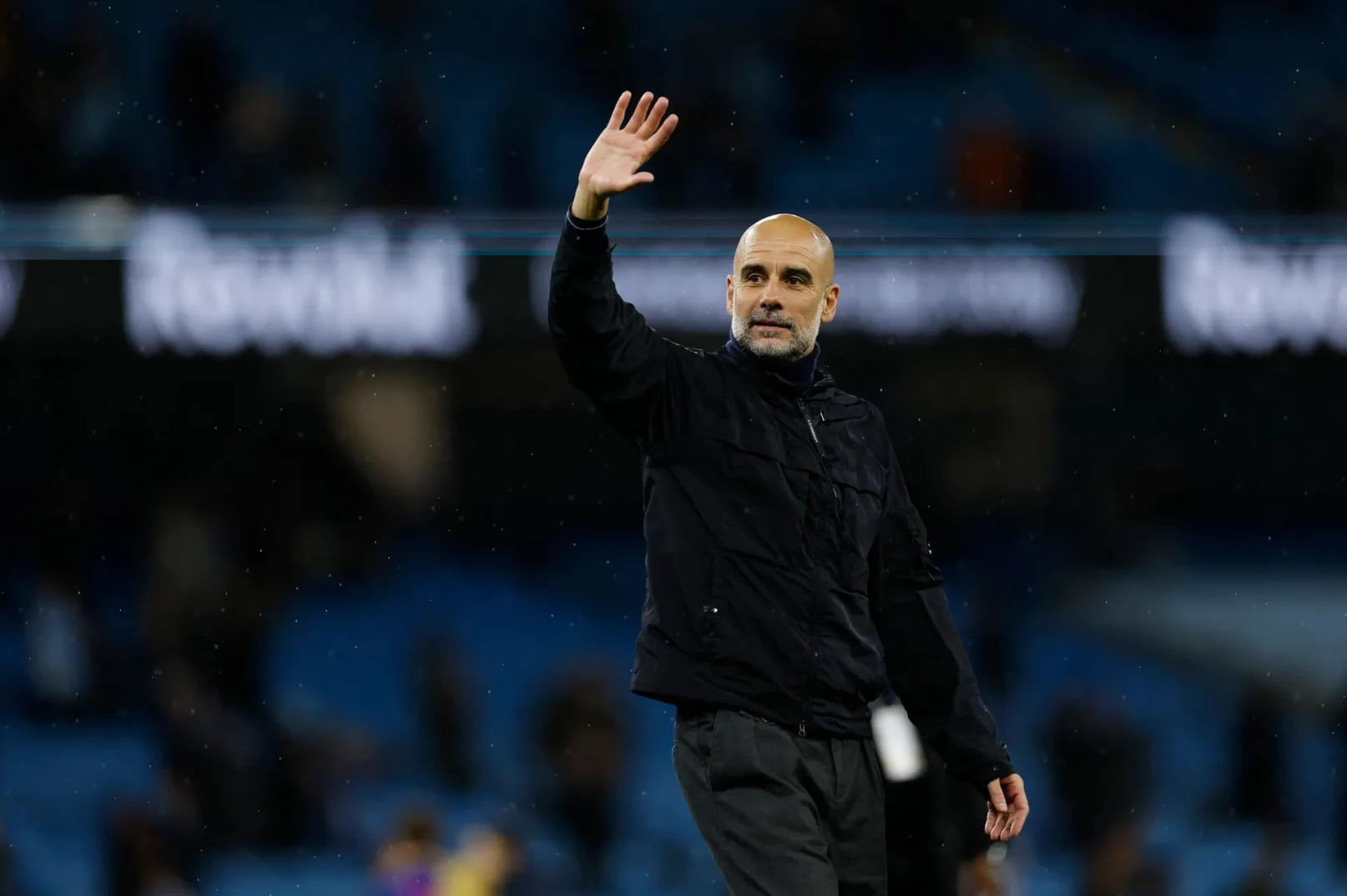 Pep Guardiola, trener Manchester Cityja, maše navijačima na stadionu u večernjim satima.