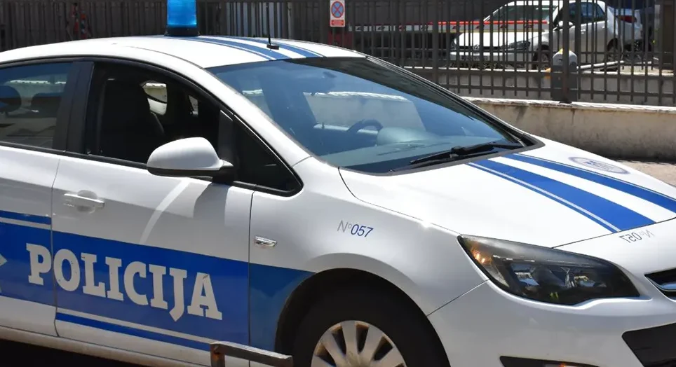 Bijelo policijsko vozilo sa plavom rotacijom na krovu i natpisom "POLICIJA" na boku.
