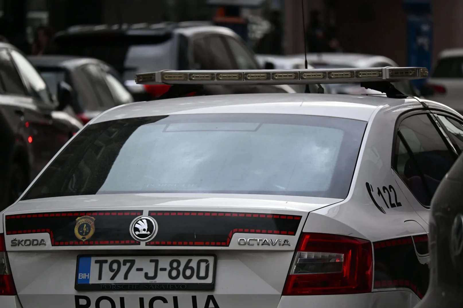Zadnji dio bijelog policijskog vozila marke Škoda Octavia sa uključenom rotacijom i policijskim oznakama.
