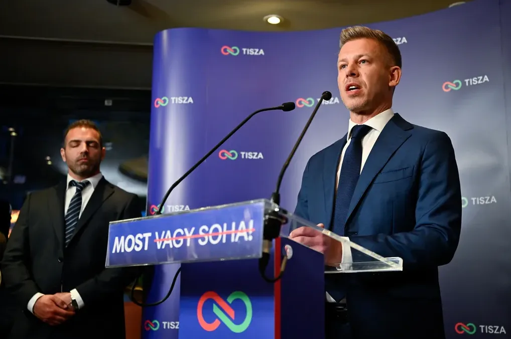 Političar u tamnom odijelu govori za govornicom sa logom "Tisza".