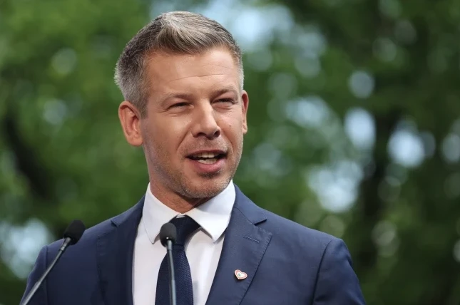 Muškarac u tamnom odijelu i bijeloj košulji sa plavom kravatom govori ispred dva mikrofona.