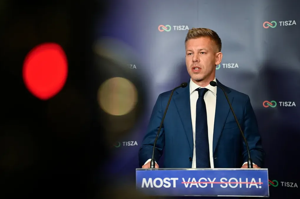 Predsjednik partije Tisza, Peter Magyar, govori za mikrofone na bini sa sloganom "Most vagy soha!"