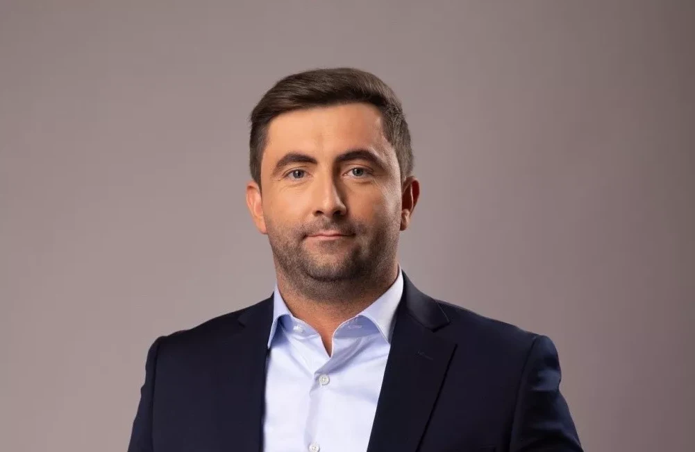 Portret uglađenog muškarca u tamnom odijelu i plavoj košulji