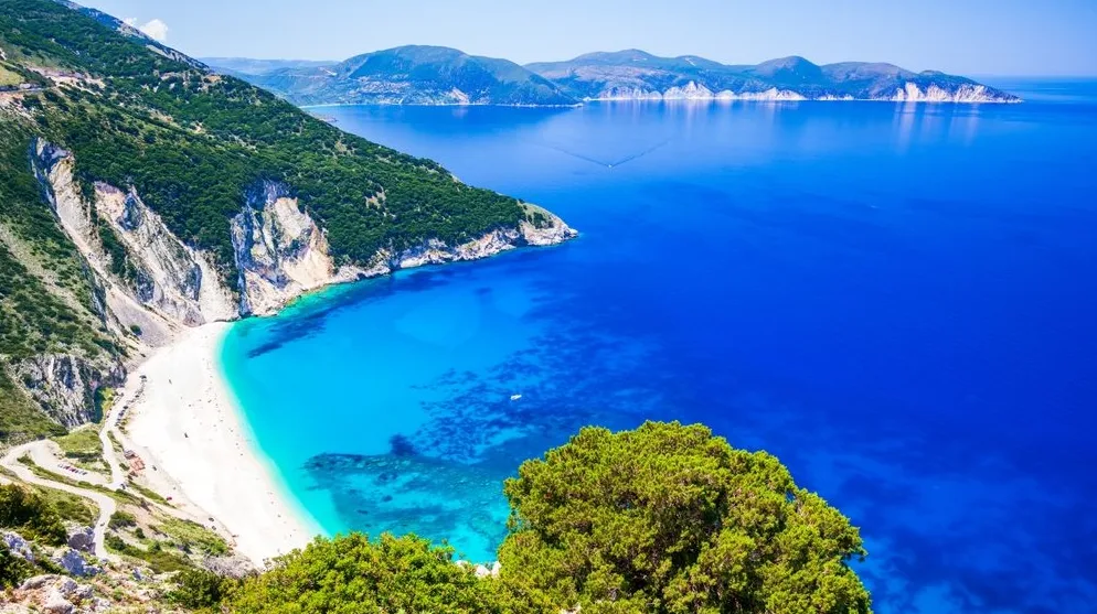 Fotografija prikazuje zadivljujući pogled na plažu Myrtos na Kefaloniji, Grčka, sa svojim bijelim šljunkom i kristalno čistim tirkiznim vodama Jonskog mora.
