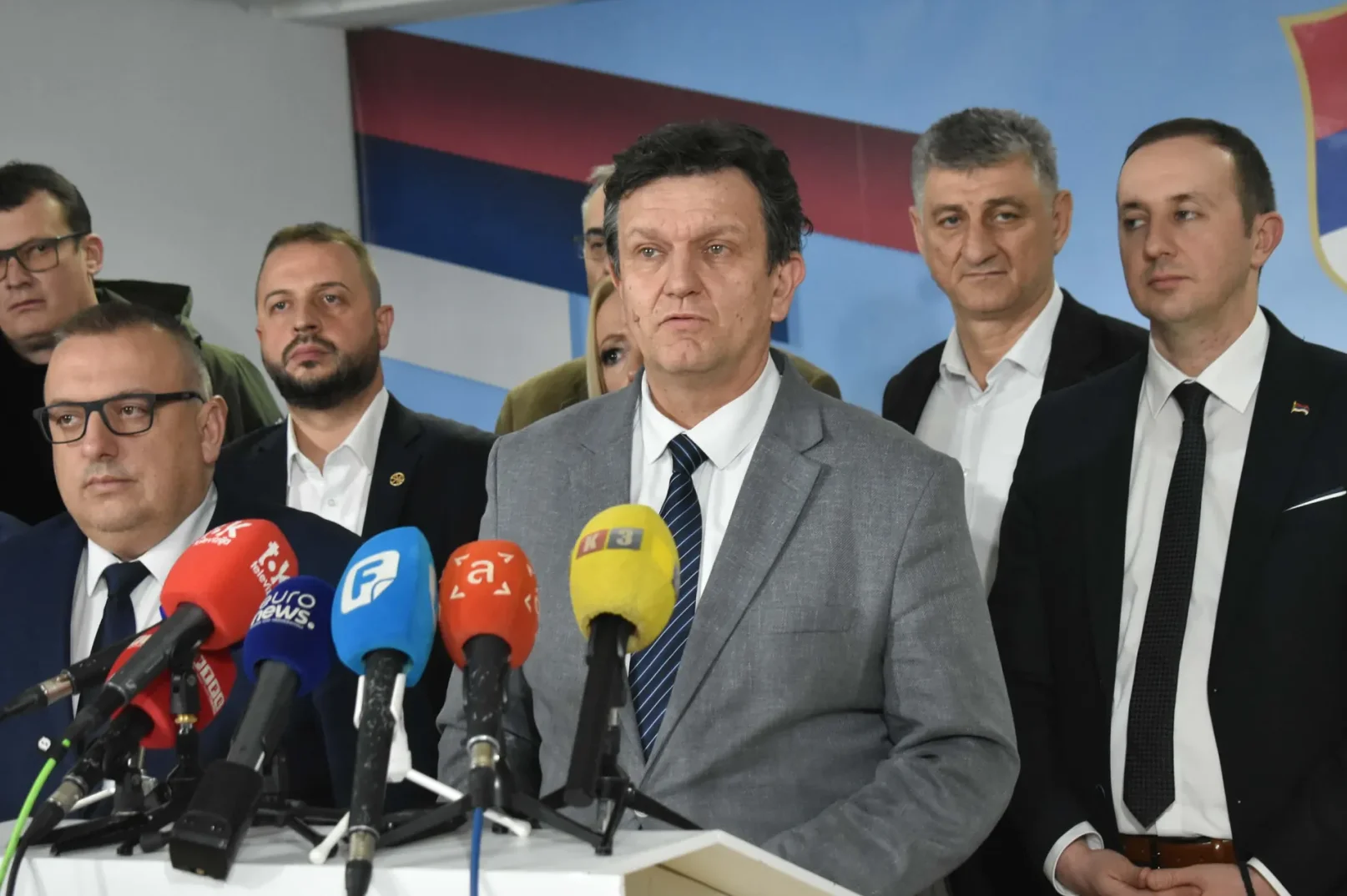 Grupa muškaraca na press konferenciji s nekoliko mikrofona ispred njih.