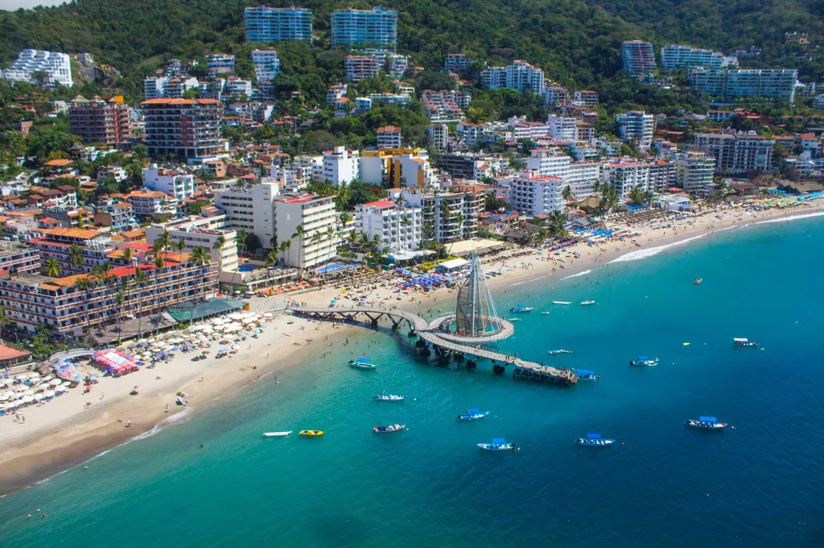 Šareni grad s više zgrada na padini planine iznad plaže