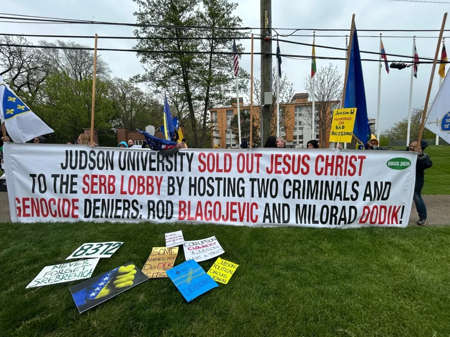 Banjaluka: Protestanti ispred Judson univerziteta drže transparent na kojem piše "JUDSON UNIVERSITY SOLD OUT JESUS CHRIST TO THE SERB LOBBY BY HOSTING TWO CRIMINALS AND GENOCIDE DENIERS: ROD BLAGOJEVIC AND MILORAD DODIK!"