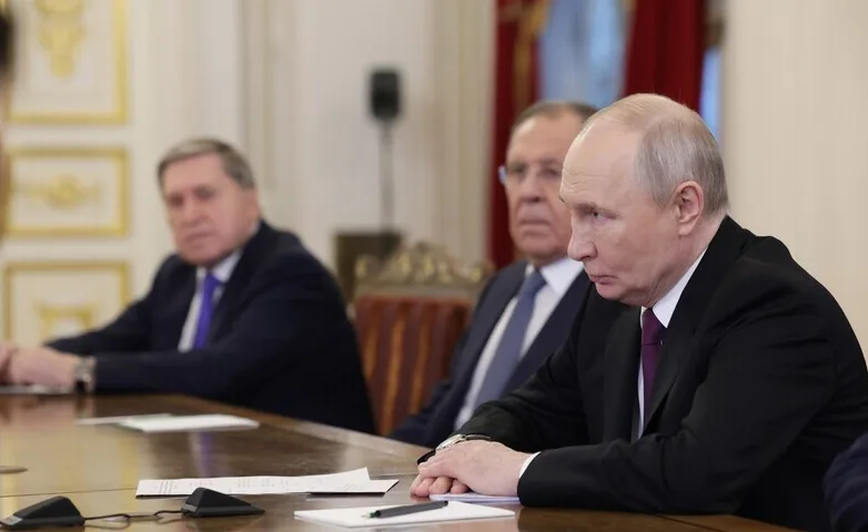 Vladimir Putin sjedi za stolom s dvojicom muškaraca, jedan od njih je ministar vanjskih poslova Sergej Lavrov.