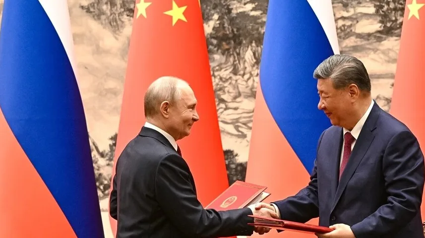 Vladimir Putin i Si Đinping rukuju se ispred zastava Rusije i Kine.