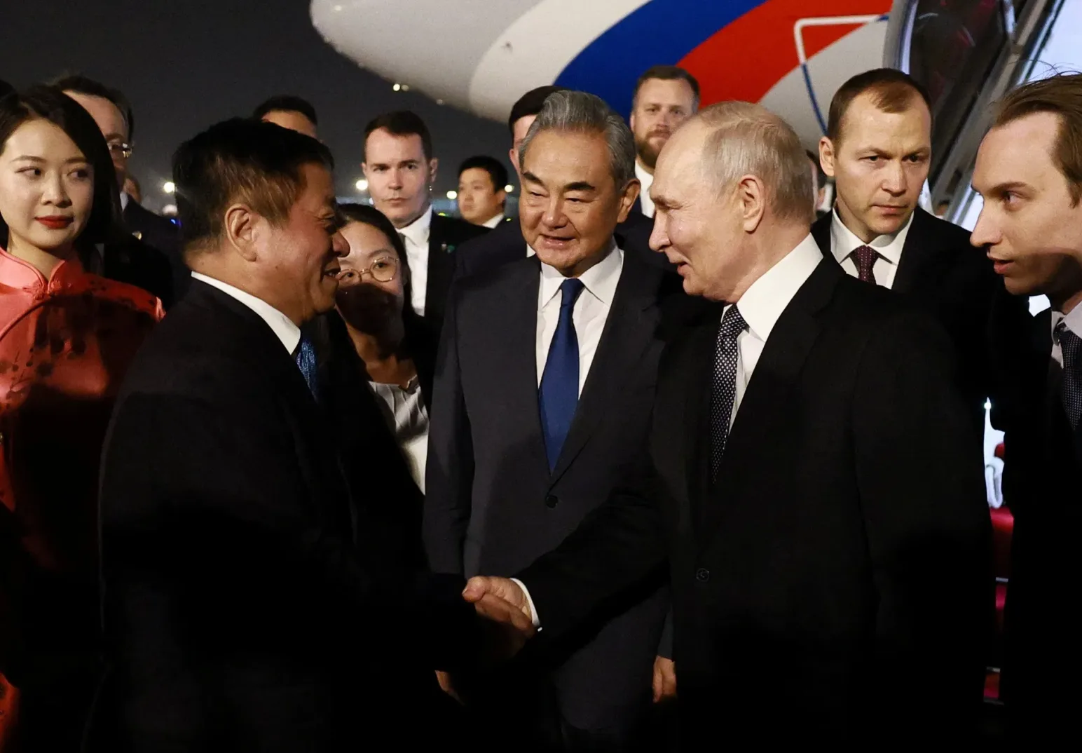 Vladimir Putin i Wang Yi se rukuju ispred aviona, okruženi zvaničnicima.
