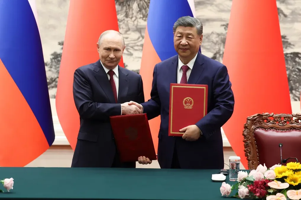 Vladimir Putin i Xi Jinping rukuju se ispred zastava Rusije i Kine držeći dokumente