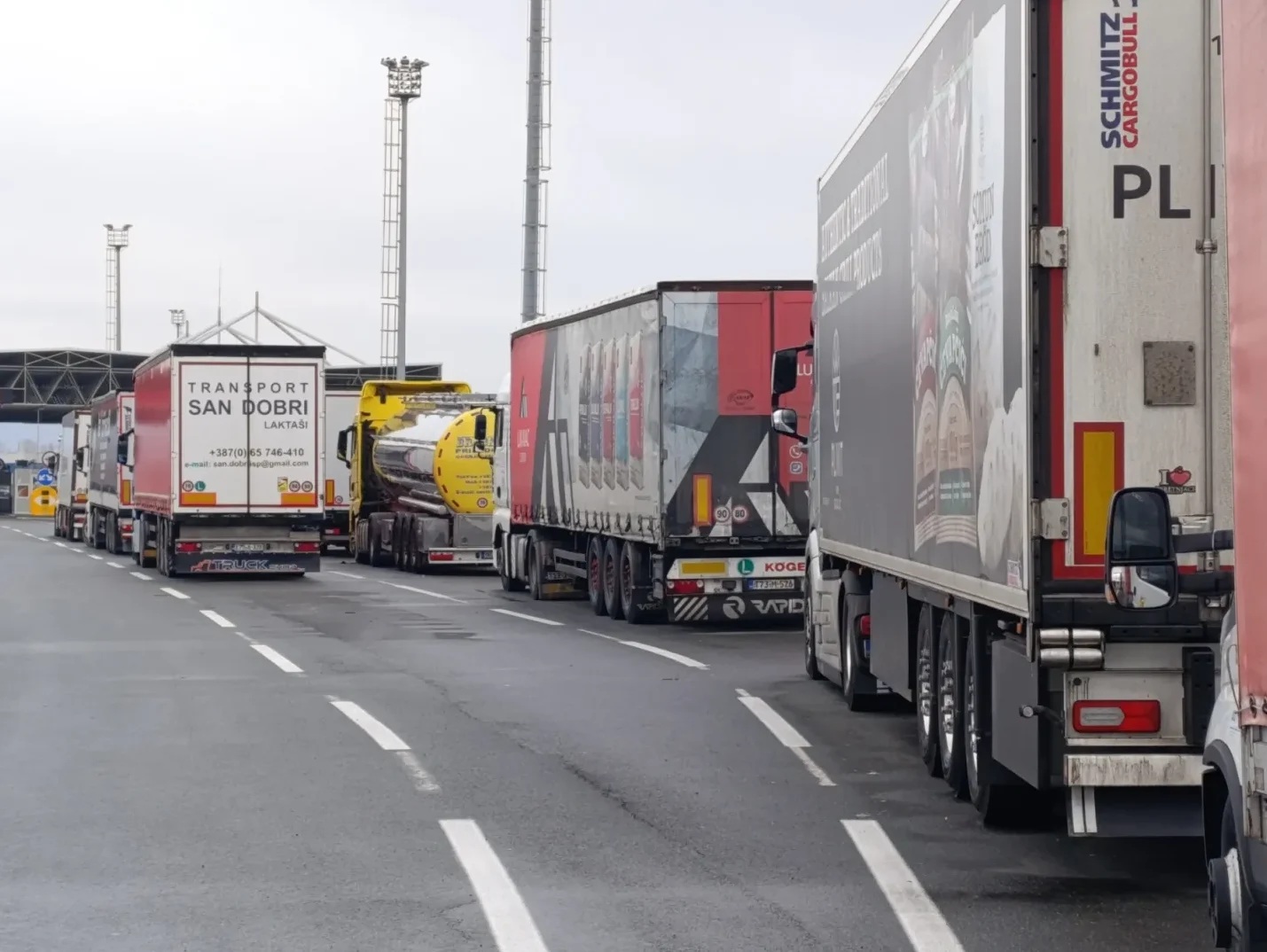 Kolona kamiona parkirana na graničnom prijelazu, sa fokusom na kamion "Transport San Dobri" iz Laktaša.