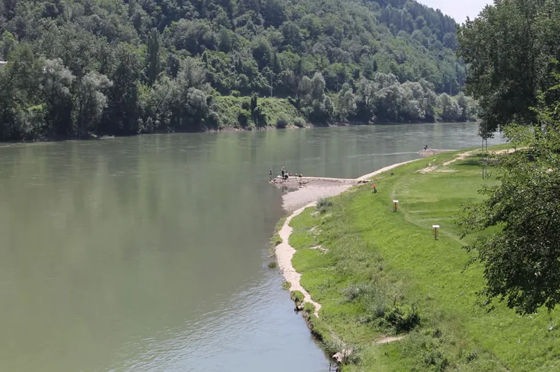 Ljudi pecaju na šljunčanoj obali rijeke.