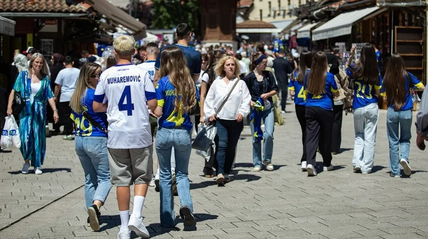 Grupa navijača u majicama sa brojevima i imenima kako hodaju ulicom
