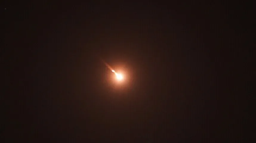Sjajni meteorit sa narančastim repom koji prolazi kroz mračno noćno nebo.