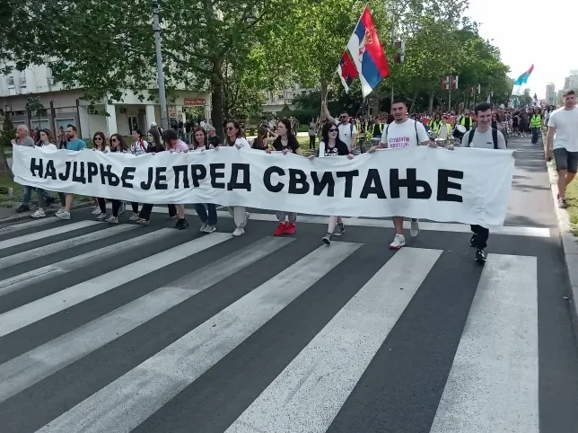 Grupa ljudi drži transparent na kojem piše "NAJDŽRĐE JE PRED SVITANJE" tokom šetnje.