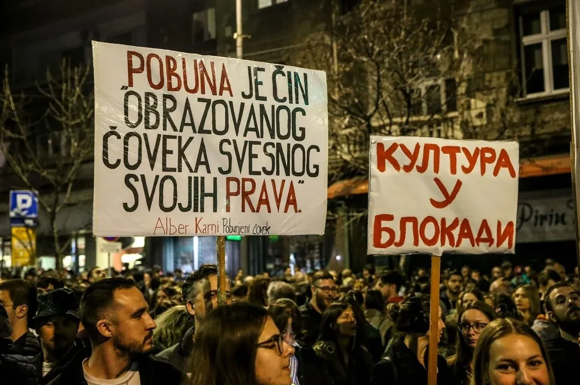 Ljudi na protestu drže transparente, jedan sa citatom Alberta Kamija o pobuni, a drugi o kulturi u blokadi.