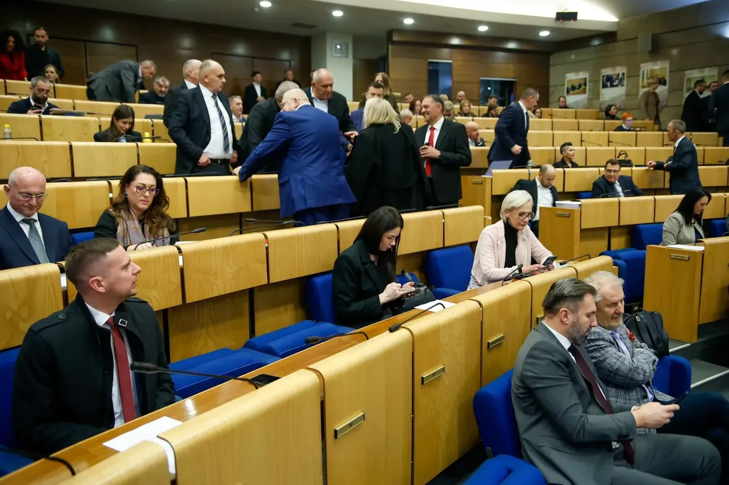 Učesnici na sjednici Skupštine, neki sjede, neki stoje i razgovaraju.