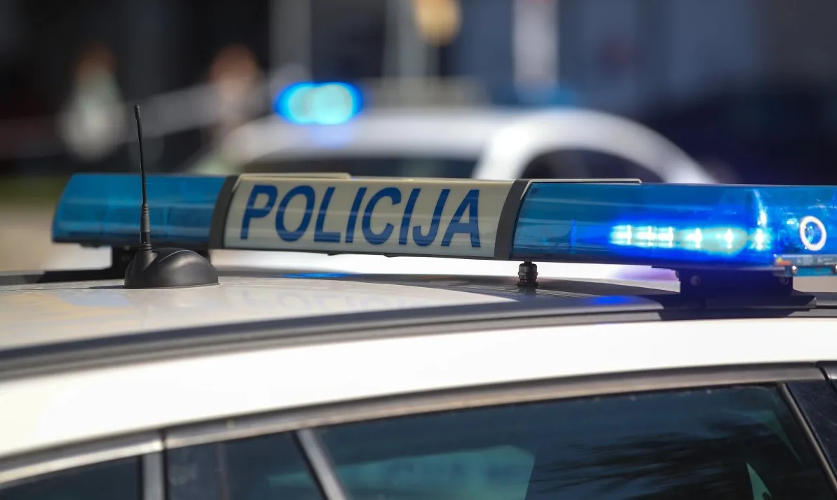 Krupni plan plave signalne sirene na krovu policijskog automobila sa natpisom "POLICIJA".