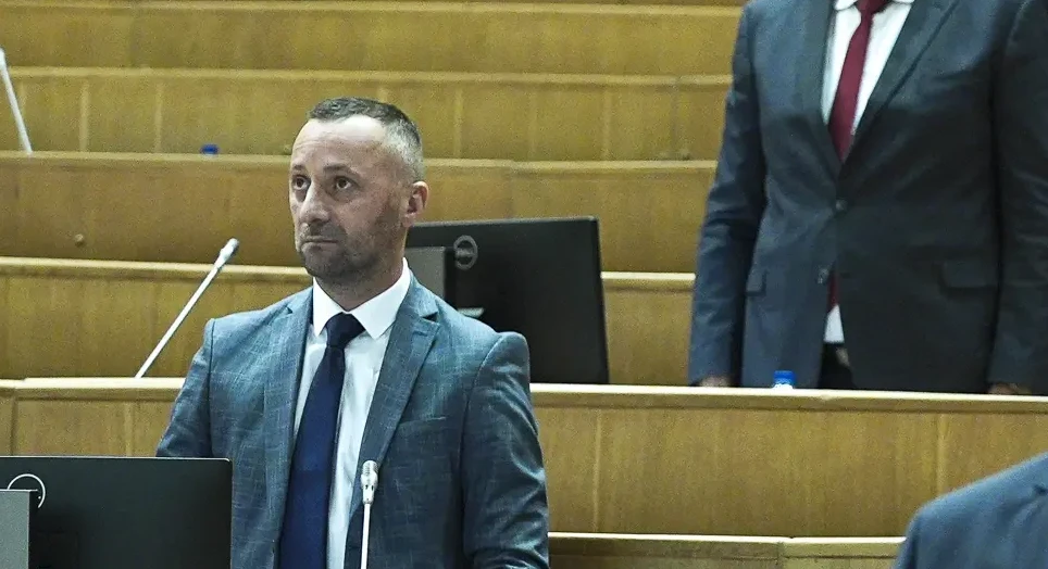 Političar u plavom odijelu sa tamnoplavom kravatom.