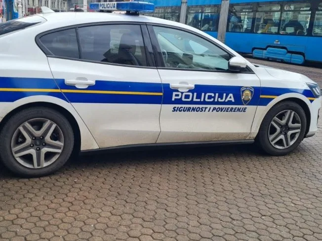 Policijsko vozilo sa plavom rotacijom na krovu i natpisima "POLICIJA" te "SIGURNOST I POVJERENJE" na boku vozila.