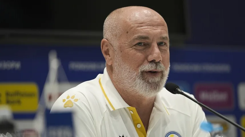 Stariji muškarac sa sijedom bradom i ćelavom glavom, obučen u bijelu majicu sa žutim detaljima, govori za mikrofonom na press konferenciji.