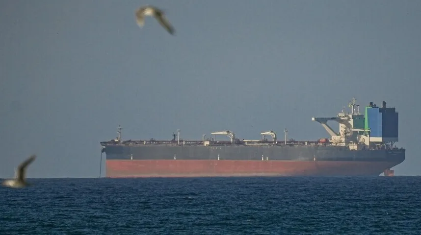 Veliki tanker usidren na mirnom moru, sa galebovima koji lete u blizini.