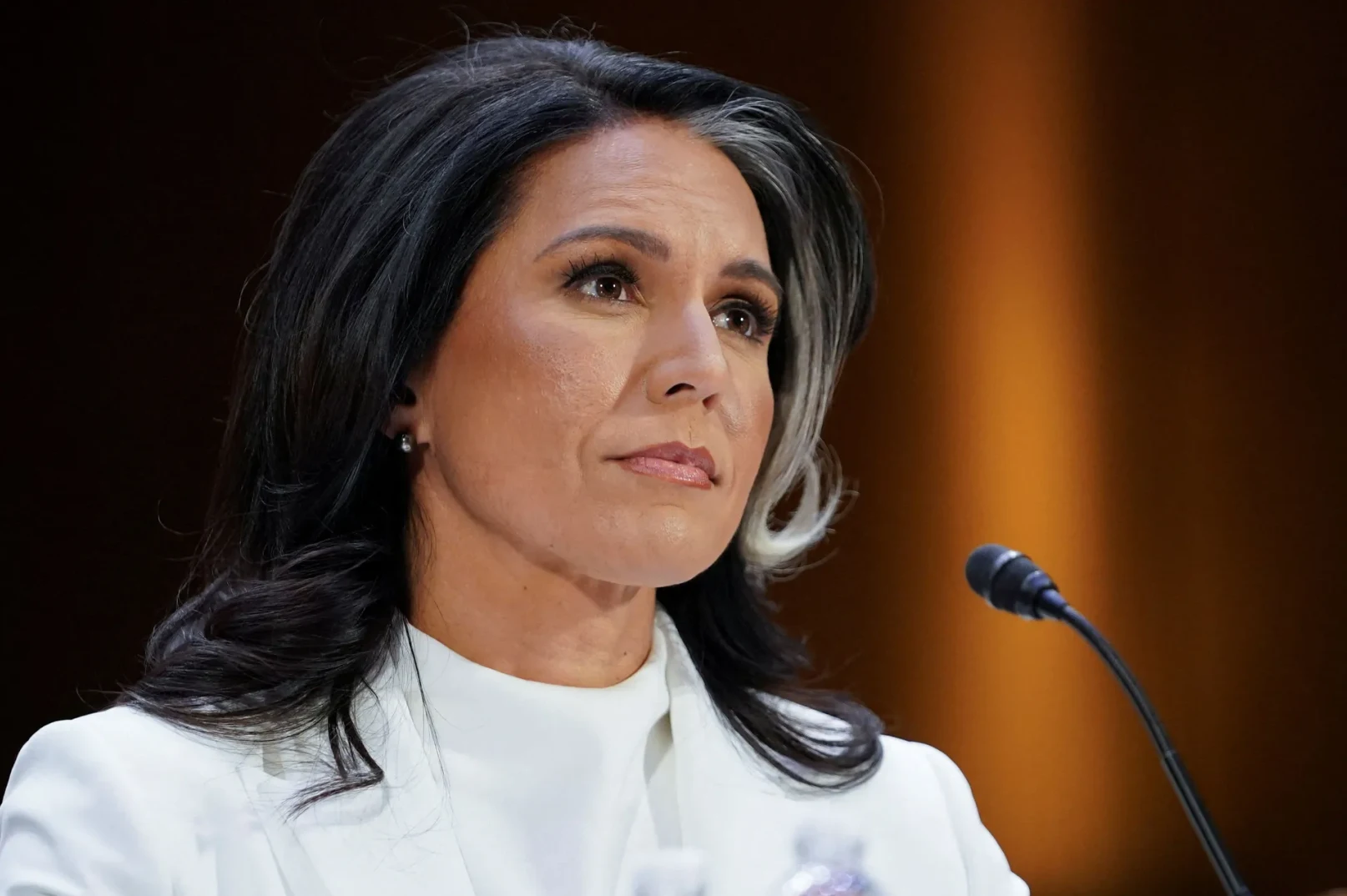 Tulsi Gabbard u bijelom odijelu sa mikrofonom