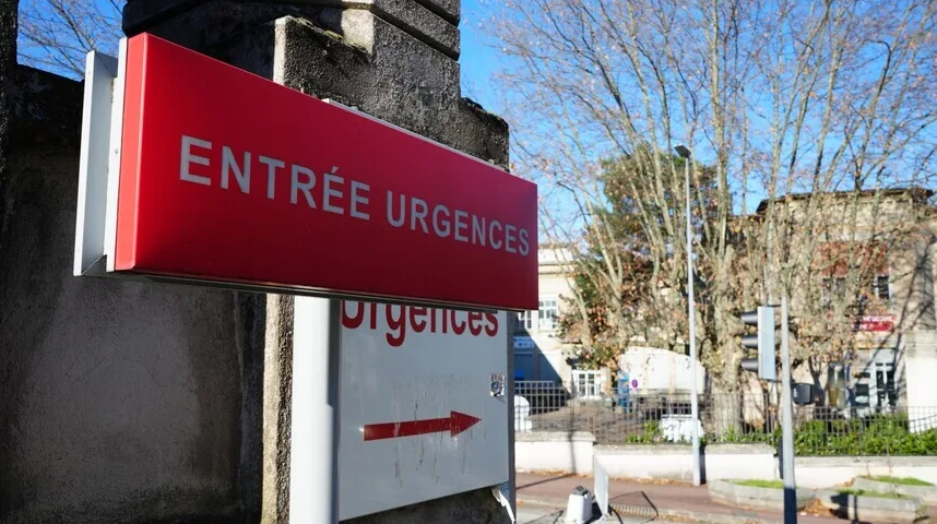 Crveni znak s natpisom "ENTRÉE URGENCES" i bijeli znak s natpisom "urgences" i crvenom strelicom koja pokazuje desno, ispred zgrade bolnice.