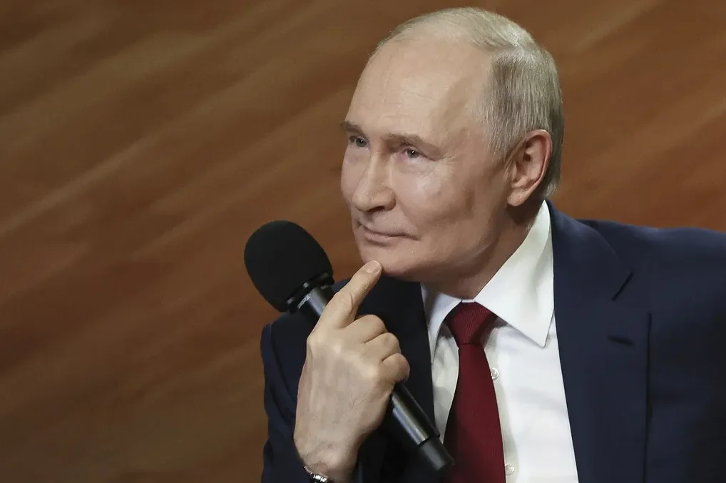 Vladimir Putin drži mikrofon prstom na bradi