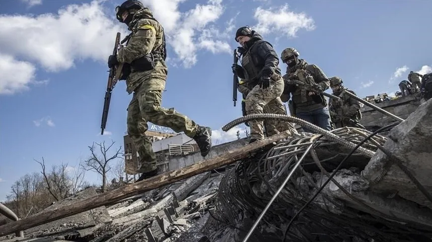 Borci u vojnim uniformama sa oružjem u rukama pažljivo prelaze preko ruševina uništenih zgrada.