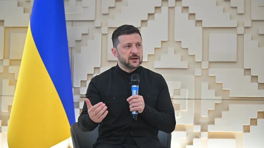 Volodimir Zelenski, ukrajinski predsjednik, govori u mikrofon pored zastave Ukrajine.