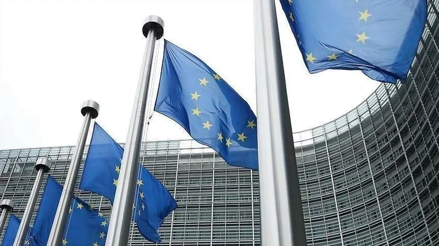 Zastave Evropske unije koje vijore na vjetru ispred moderne zgrade sa staklenom fasadom.