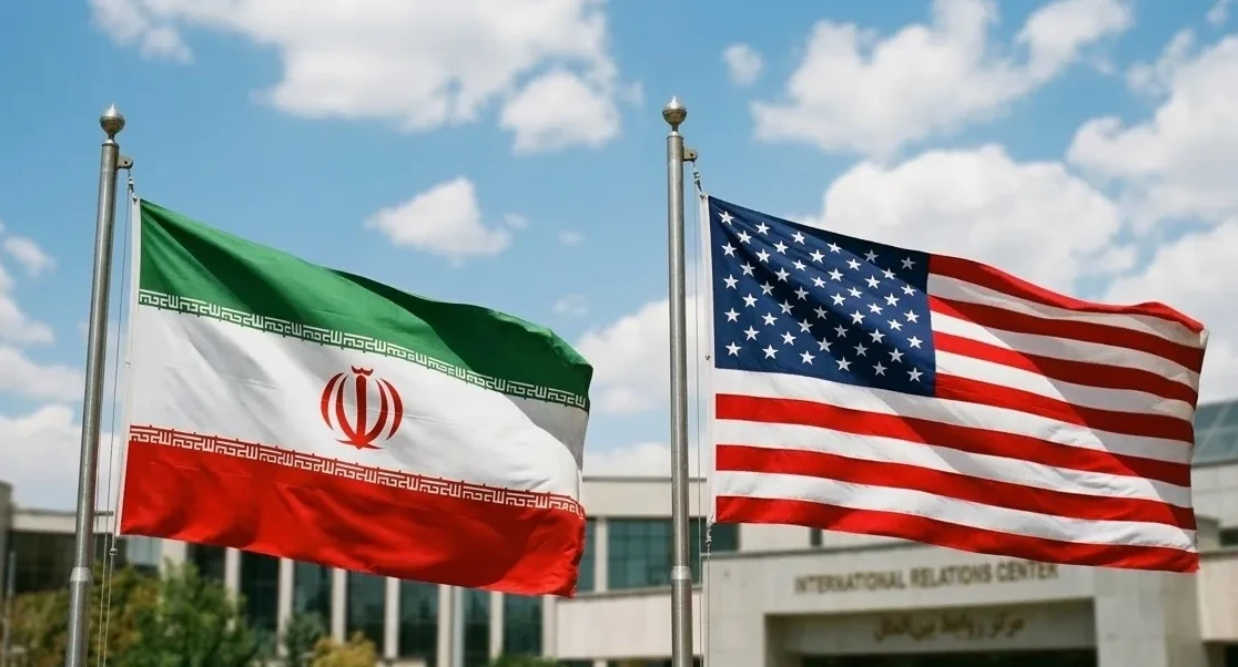 Zastava Irana i zastava Sjedinjenih Američkih Država vijore se jedna pored druge na jarbolima, s plavim nebom i oblacima u pozadini.