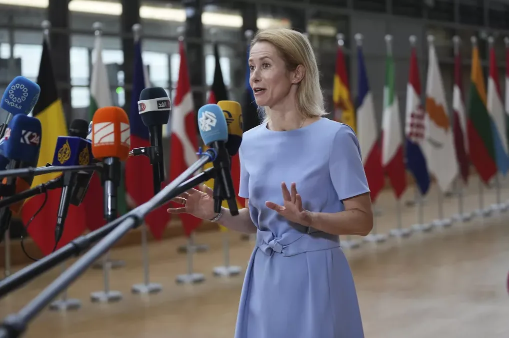 Žena u plavoj haljini obraća se novinarima ispred zastava raznih zemalja