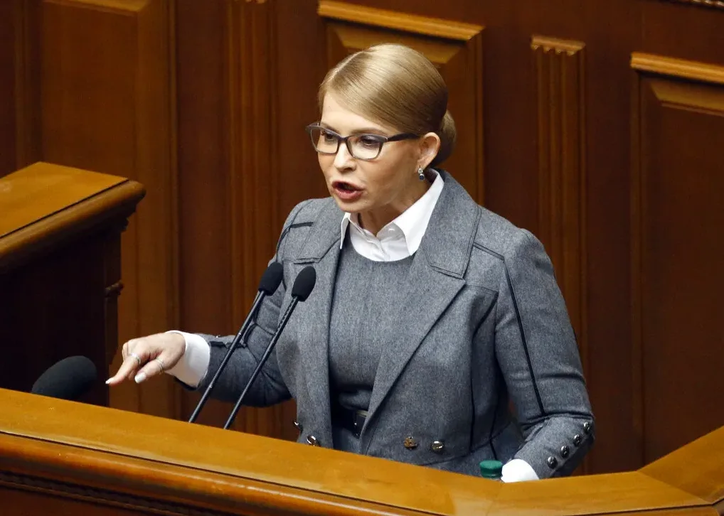 Političarka sa naočalama govori iza podijuma u parlamentu.