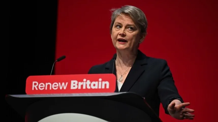 Žena kratke sijede kose u crnom sakou govori iza podijuma sa natpisom "Renew Britain"