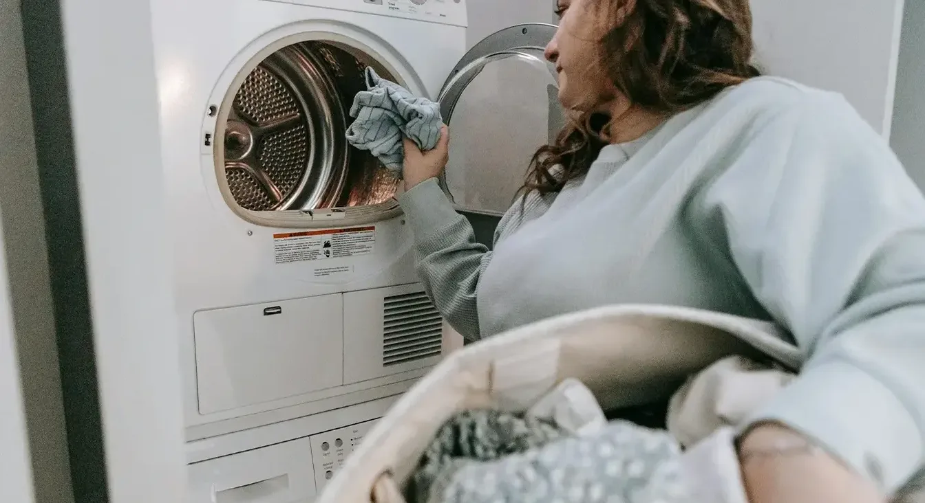 Žena stavlja veš u mašinu za sušenje