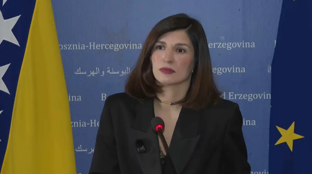 Žena u crnom sakou ispred zastave Bosne i Hercegovine i Evropske unije