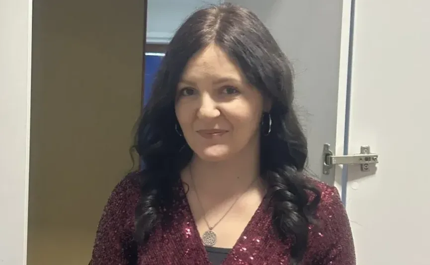 Portret žene sa tamnom kosom, velikim obručastim minđušama i ogrlicom sa kružnim privjeskom.