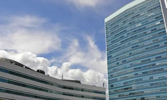 Moderna staklena zgrada naspram plavog neba sa oblacima
