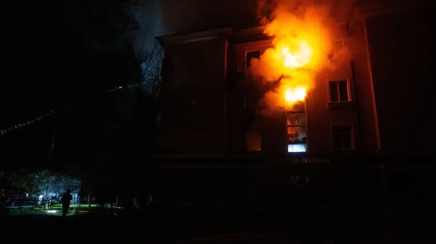 Zgrada zahvaćena plamenom noću, sa dimom koji kulja iz prozora.