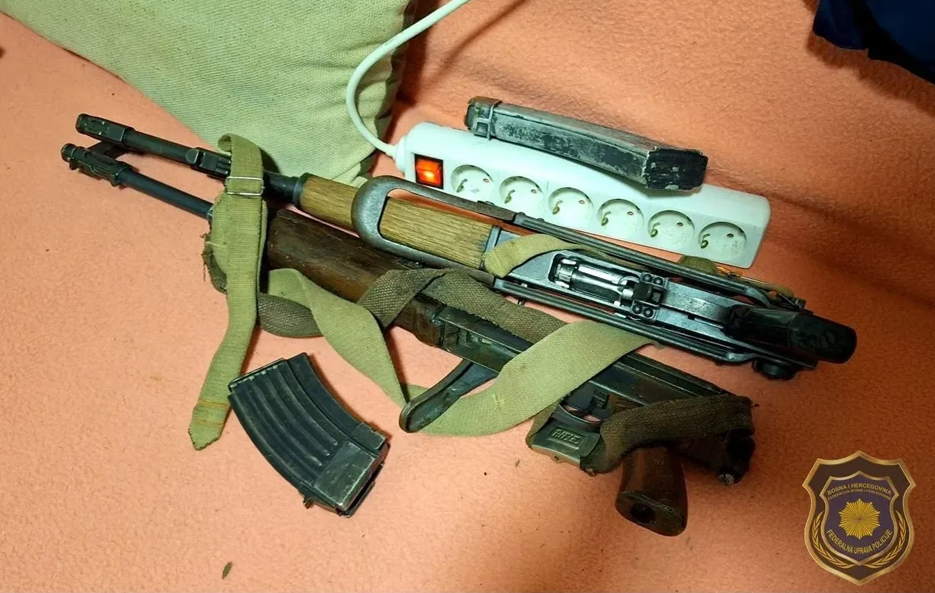 Automatska puška sa pripadajućim okvirom sa streljivom, kaišem i produžnim kablom sa utičnicama, uz amblem Federalne uprave policije.