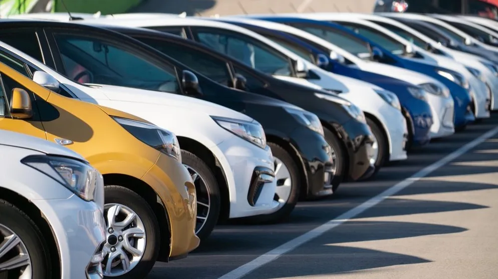 Redovi novih automobila različitih boja parkiranih na otvorenom prostoru.