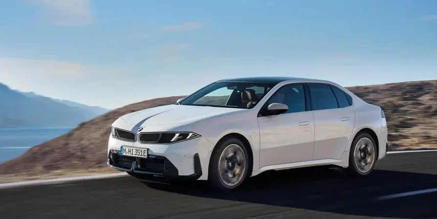 Bijeli BMW serije 7 vozi se putem pored mora i planina