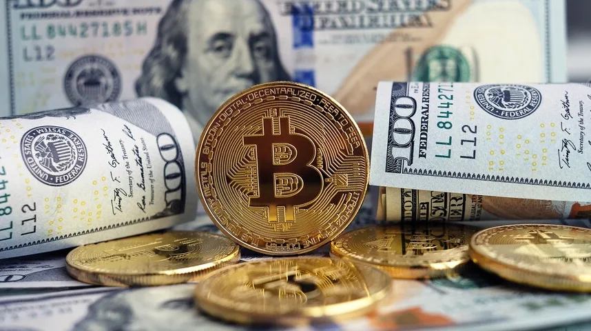 Zlatni Bitcoin novčić sa američkim dolarima u pozadini