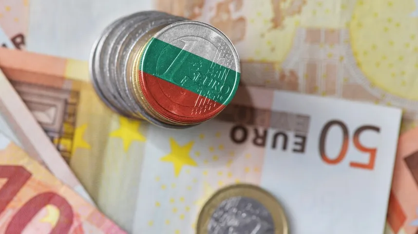 Novčić sa zastavom Bugarske na hrpi novčića iznad eura novčanica.